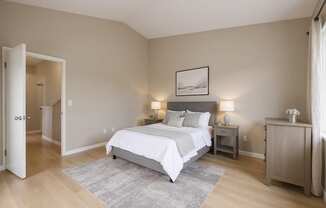 A bedroom with a large bed and a nightstand with a lamp.