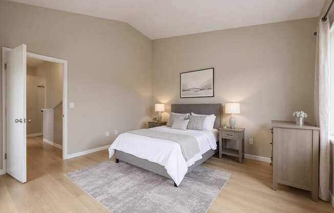 A bedroom with a large bed and a nightstand with a lamp.