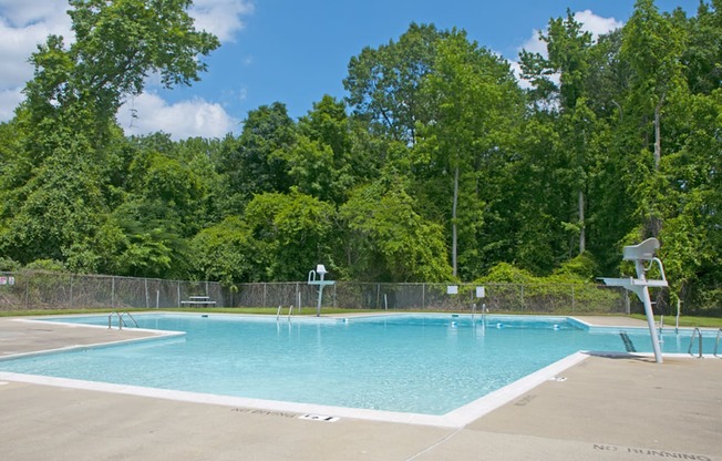 a swimming pool with a fence around it and trees in the background