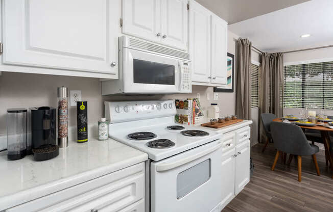 A white kitchen with a stove, microwave, and oven.