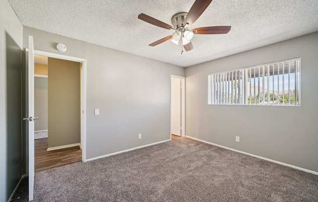 A room with a ceiling fan and a window with blinds.