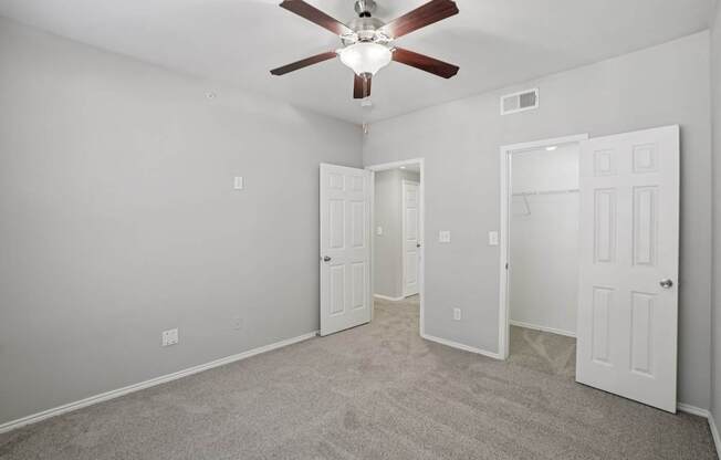 A room with a ceiling fan and three doors.