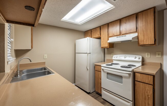 A kitchen with a stove, sink, and refrigerator.