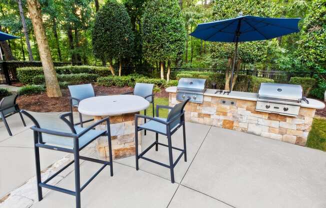 a patio with a bbq and a table and chairs