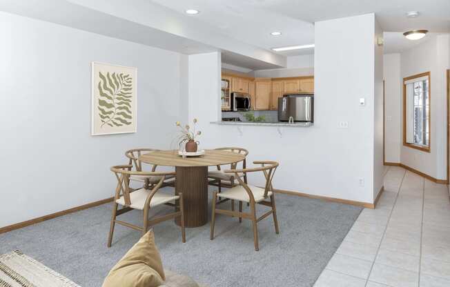 a dining area with a table and chairs and a kitchen in the background