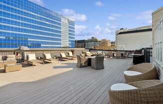 a rooftop deck with chairs and tables on a skyscraper