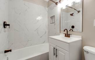 A white bathroom with a marble wall and a white sink.