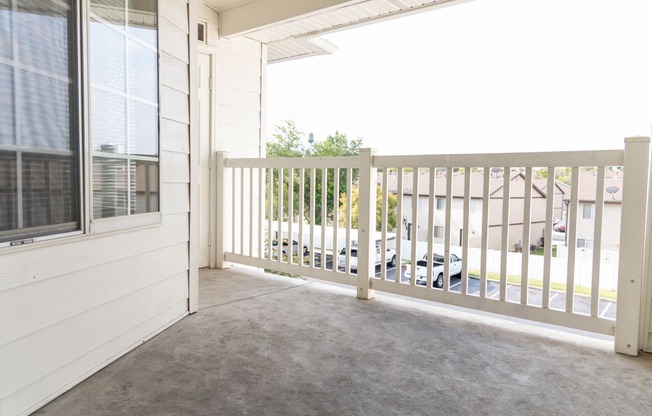 a covered porch with a white railing and a white house