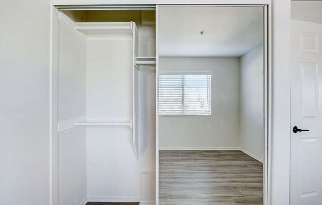 an empty bedroom with a closet and a window
