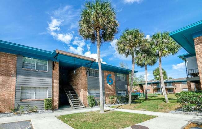 Exterior shot of Watermark Apartments in Lakeland, Fl. Buildings are brick with grey siding around windows, and front building has a large blue 6.