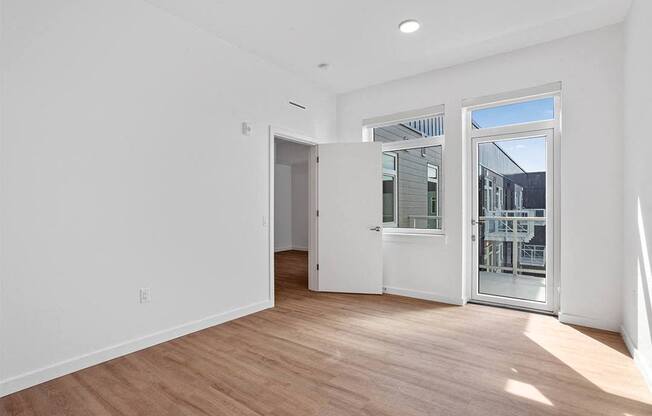 a living room with white walls and a door to a balcony
