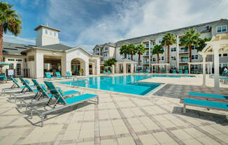 a swimming pool with chaise lounge chairs and a building in the background