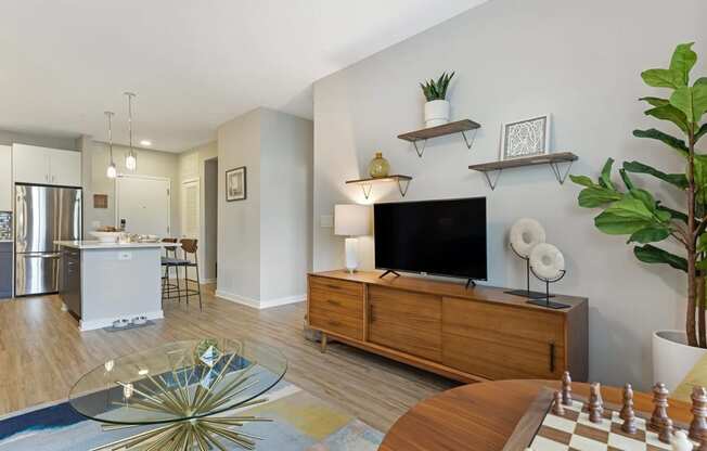a living room with a large tv and a kitchen in the background