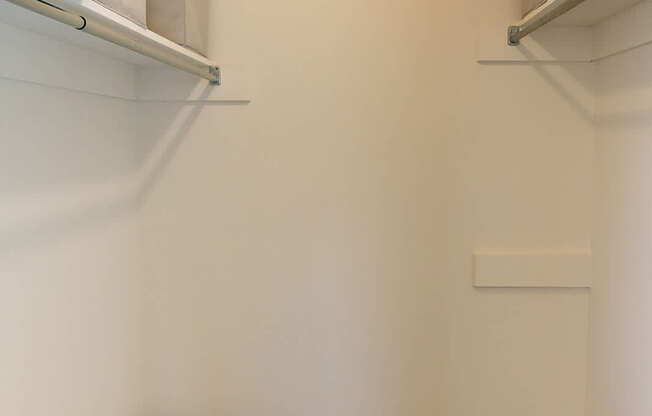 A walk in closet with a striped basket on the floor.