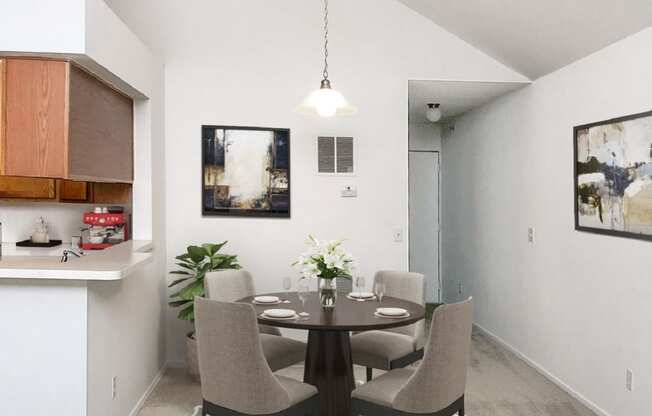 a dining area with a table and chairs and a kitchen in the background
