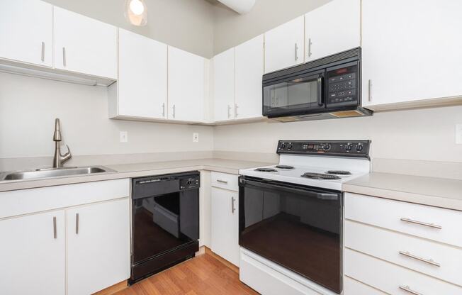 a kitchen with white cabinets and a black oven and microwave