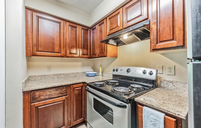 a kitchen with wood cabinets and granite counter tops and a stove top oven