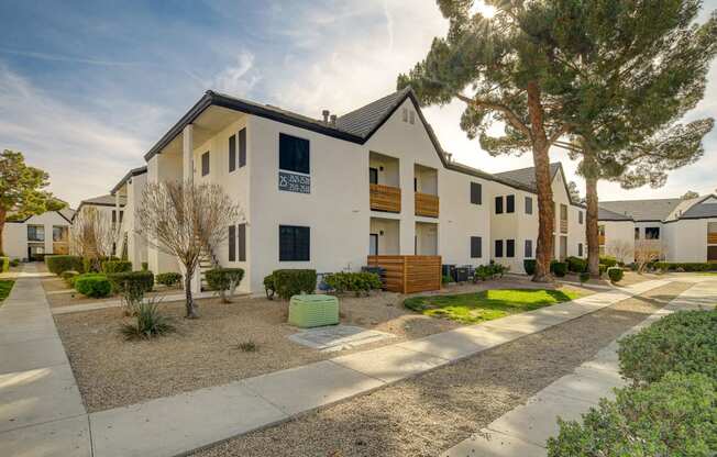 a street view of a white apartment complex with a tree in the foreground