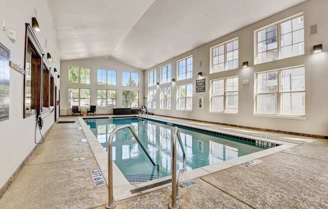 the indoor pool is spacious and has windows and a glass railing around it