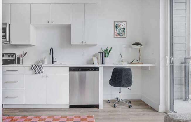 A kitchen with white cabinets and a black chair.