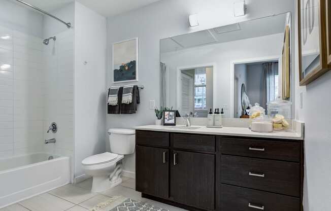 a bathroom with a toilet sink mirror and shower in a 555 waverly unit