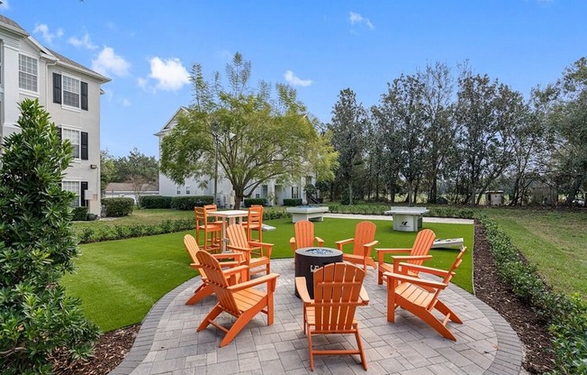 an outdoor patio with orange chairs and a fire pit