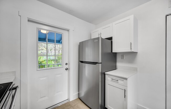 a white kitchen with a refrigerator and a window