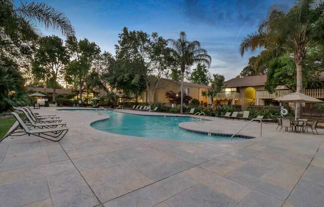 a swimming pool with chairs and umbrellas at Summerwood Apartments, Santa Clara, CA