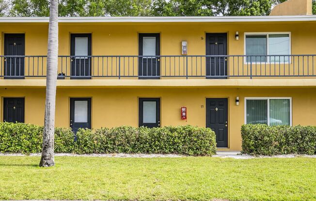 a yellow building with a balcony and a sidewalk