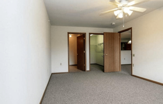 an empty living room with a ceiling fan and a closet