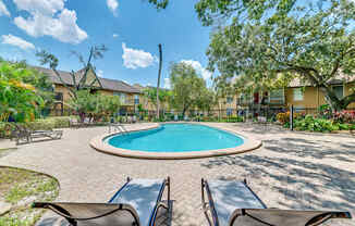 a backyard with a pool and patio with chairs