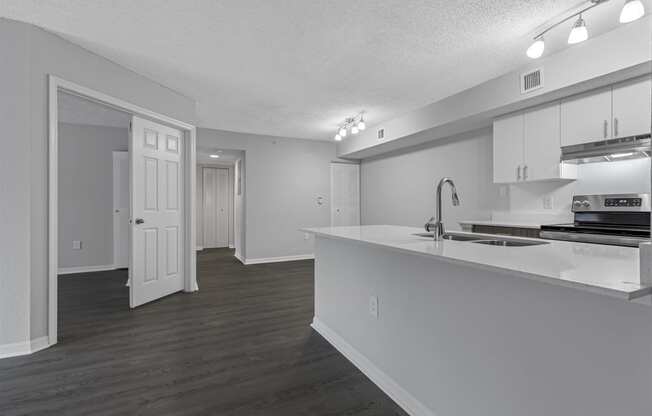 an empty kitchen and living room with white cabinets and a white counter top