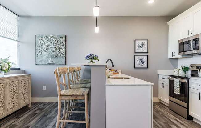 A kitchen with a white island and wooden chairs.
