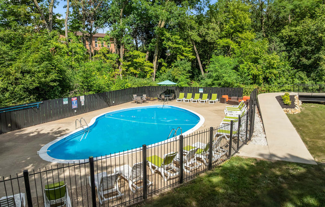 A pool surrounded by a fence and trees.