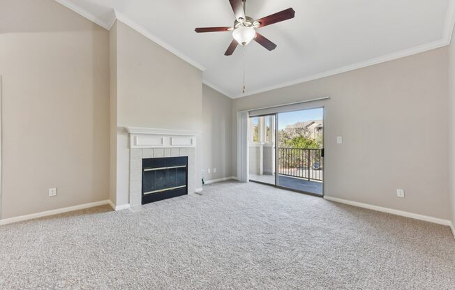 A spacious living room with a fireplace and a ceiling fan.