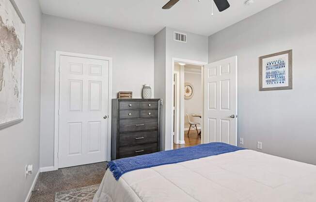A bedroom with a bed, dresser, and ceiling fan.