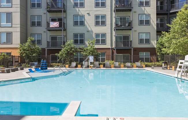 an outdoor pool with an apartment building in the background