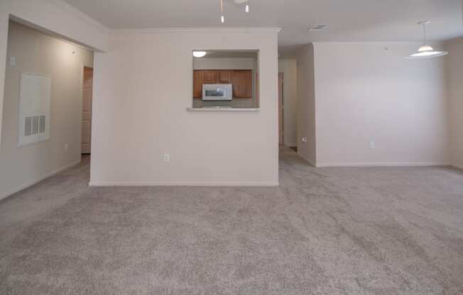 an empty living room with a kitchen in the corner