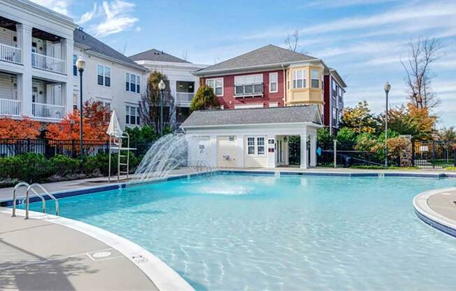 a large swimming pool with a fountain in front of an apartment building