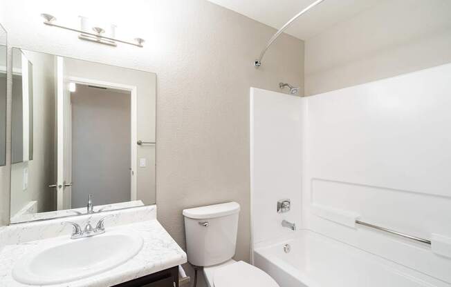 A white bathroom with a sink, toilet, and bathtub.