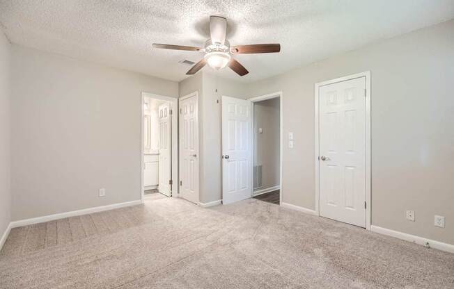 A room with a ceiling fan and carpeted floor.