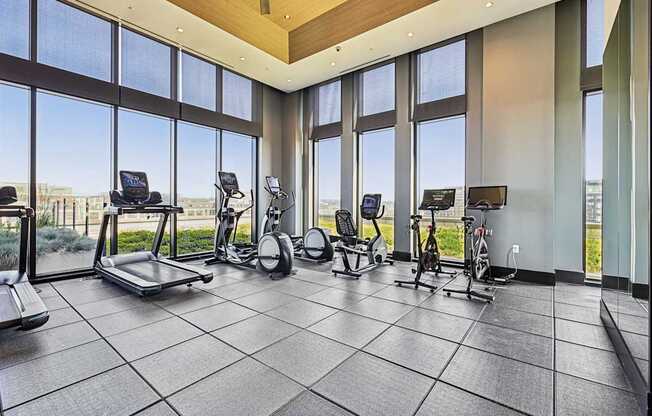 A spacious gym with treadmills, stationary bikes, and elliptical machines.