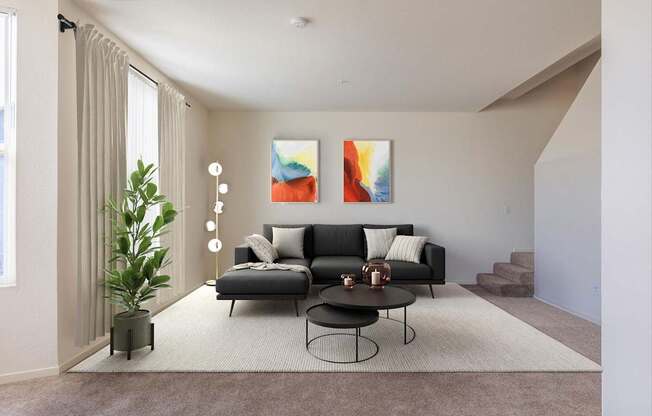 A living room with a black couch, a small table, and a painting on the wall.