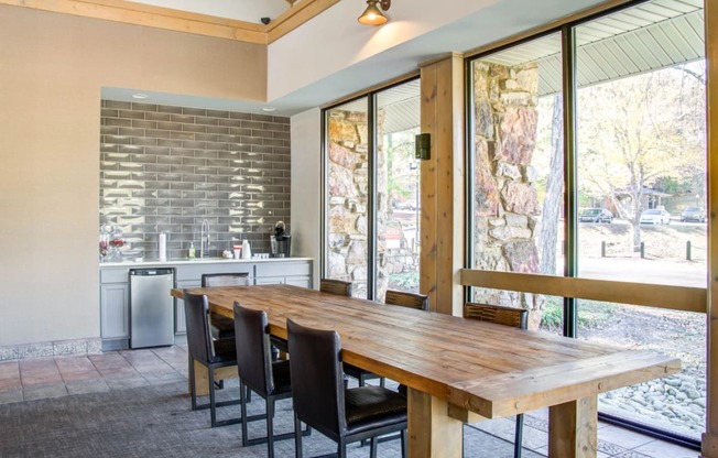 a dining area with a wooden table and chairs and a kitchen with large windows