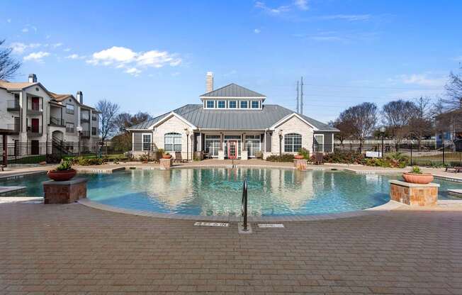 A large swimming pool in front of a building with a fountain in the middle.