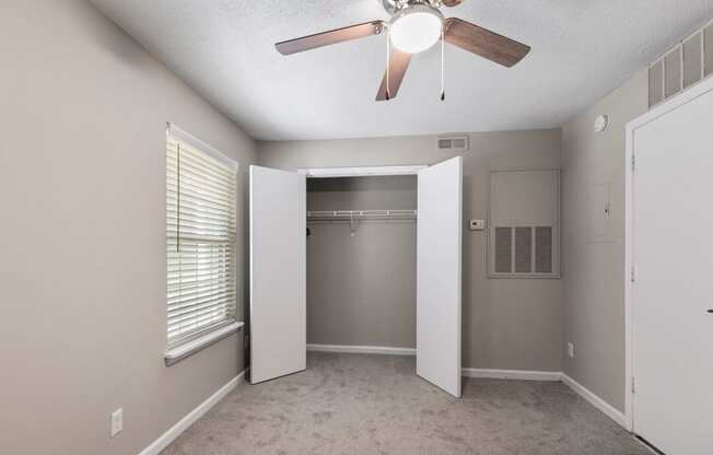 an empty bedroom with a ceiling fan and a closet