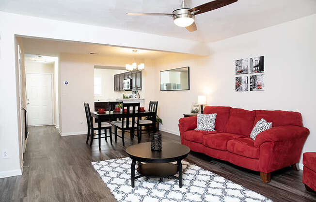 A living room with a red couch and a dining table.
