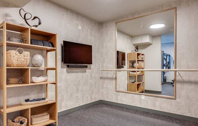 A room with a mirror, a shelf with baskets and decorations, and a flat screen TV mounted on the wall.