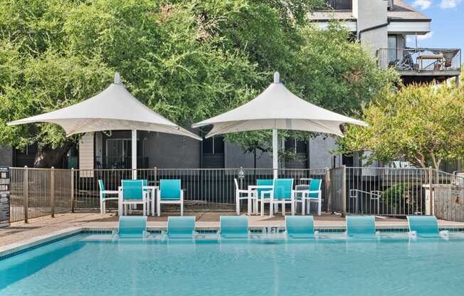 a swimming pool with blue chairs and umbrellas next to a resort pool