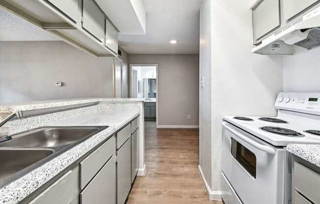 A kitchen with a stove, sink, and cabinets.